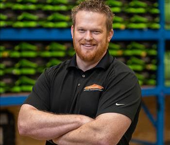 Adam is a white male with red hair wearing a black servpro polo